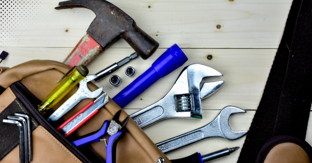 a collection of essential hand tools spread out on a light wooden surface